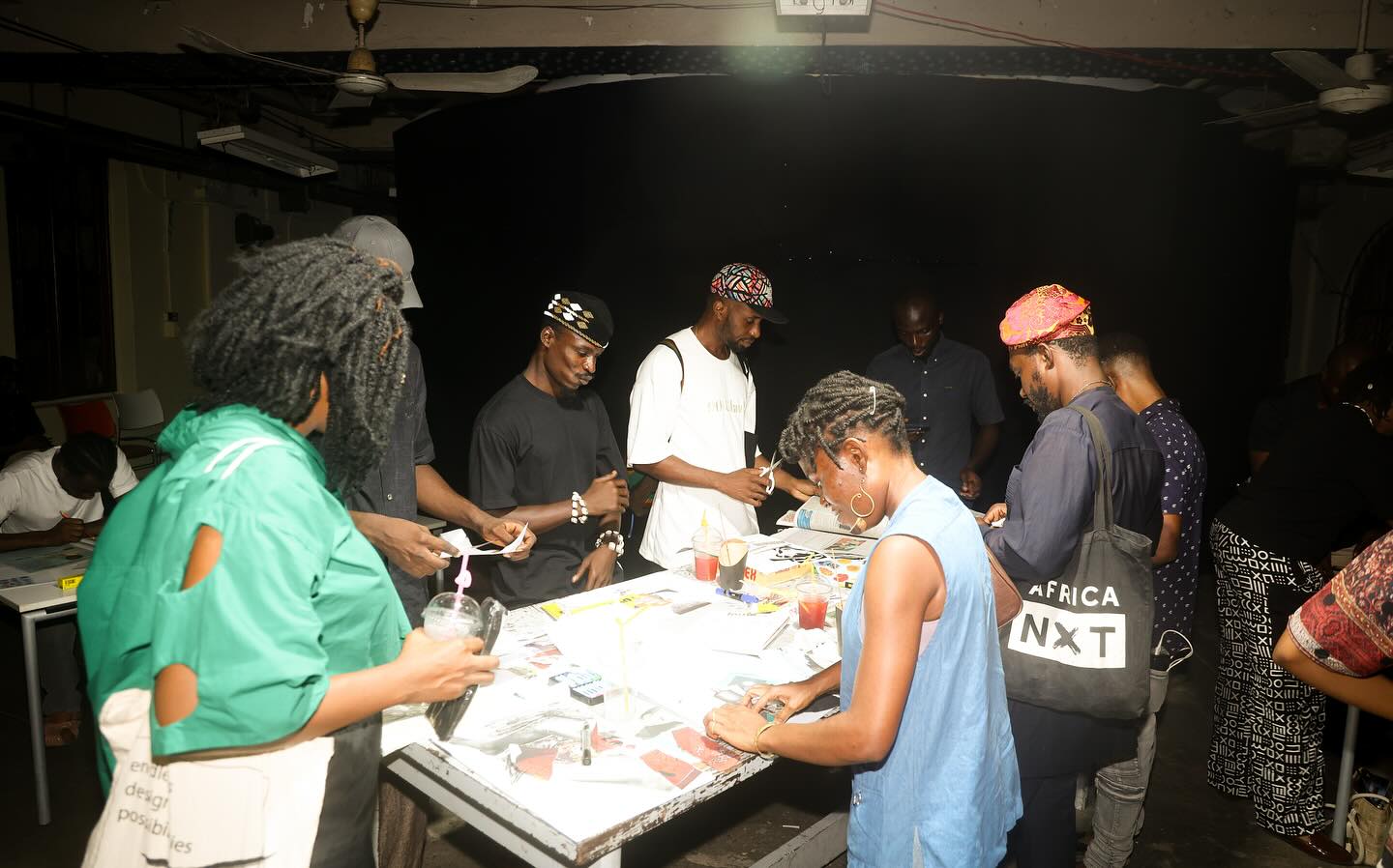 Participants at a collage and print-making table during the Kedu Lagos public programme, printed materials spread across the surface