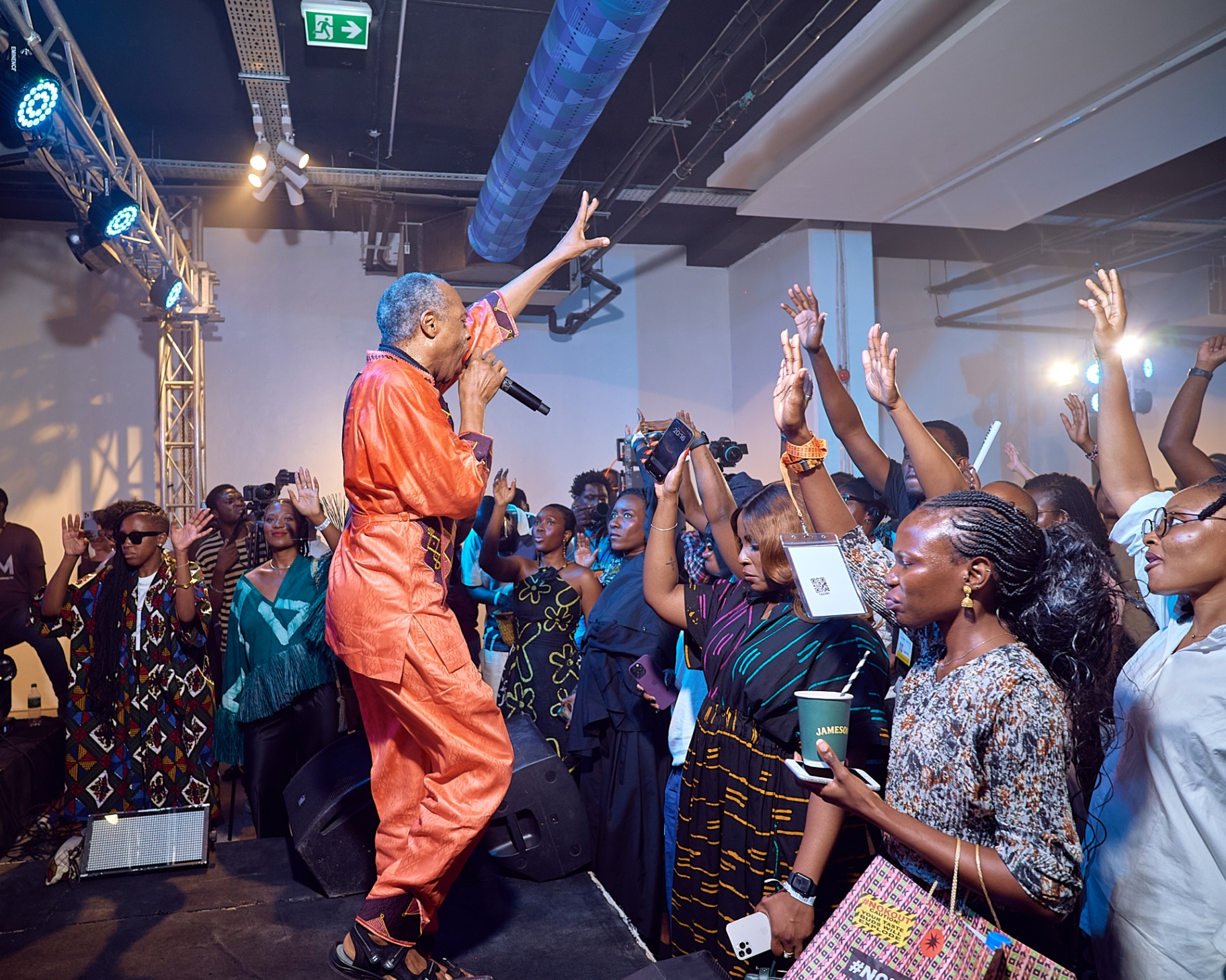Femi Kuti performing on stage with the audience raising their hands at Afrobeat Rebellion