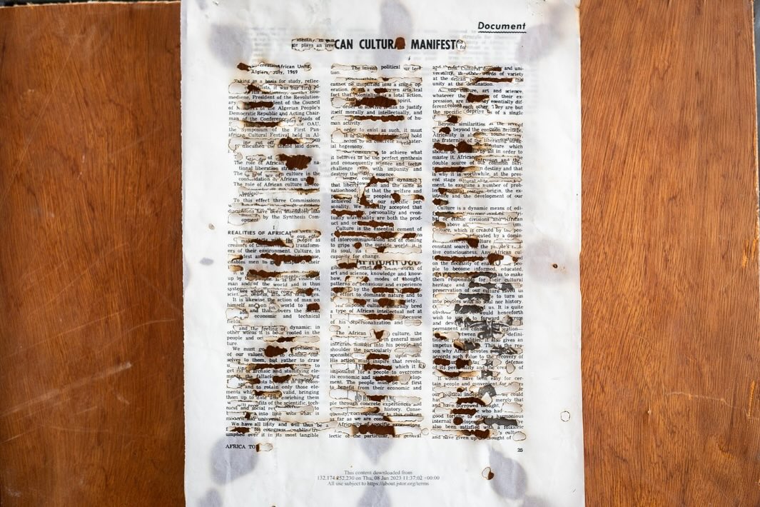 Redacted and burnt page of an African Cultural Manifesto laid on a wooden surface